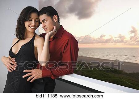 Stock Photography - Hispanic couple hugging on balcony. Fotosearch