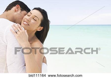 Picture - Hispanic couple hugging on beach. Fotosearch