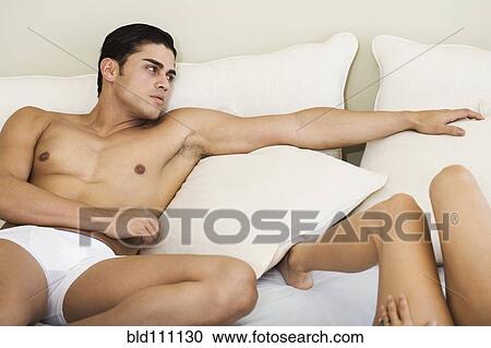 Stock Image - Hispanic couple laying on bed. Fotosearch