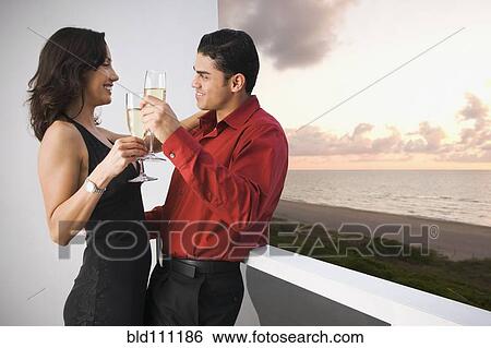 Hispanic couple toasting each other on balcony View Large Photo Image Stock Photograph - Hispanic couple toasting each other on balcony. Fotosearch