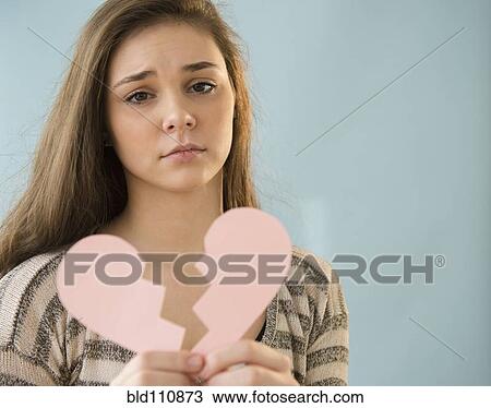 Stock Image - Hispanic girl holding broken heart shape. Fotosearch