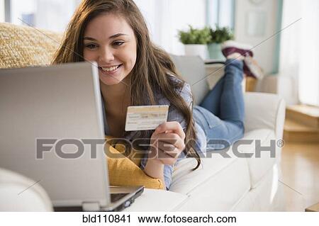 Stock Image - Hispanic girl shopping on sofa. Fotosearch