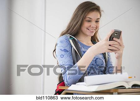 Hispanic girl using cell phone at desk View Large Photo Image Stock Image - Hispanic girl using cell phone at desk. Fotosearch
