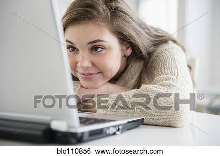 Stock Photograph - Hispanic girl using laptop at desk. Fotosearch