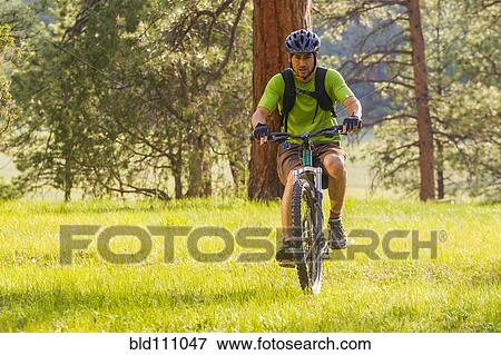 Hispanic man riding mountain bike in meadow View Large Photo Image Stock Photo - Hispanic man riding mountain bike in meadow. Fotosearch