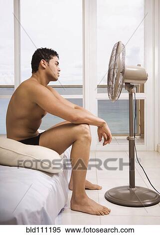 Stock Photography - Hispanic man sitting in front of fan. Fotosearch