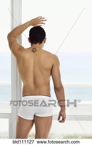 Stock Photo - Hispanic man standing at window. Fotosearch
