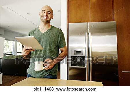 Hispanic man using tablet computer in kitchen View Large Photo Image Stock Photo - Hispanic man using tablet computer in kitchen. Fotosearch