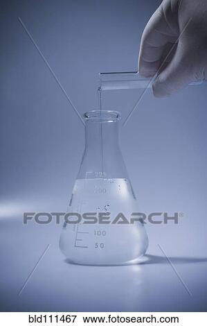 Stock Photo - Hispanic scientist pouring liquid into beaker. Fotosearch
