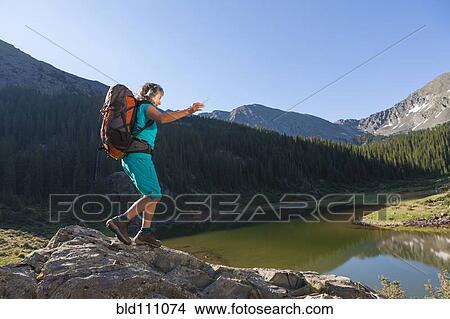 Picture - Hispanic woman hiking on boulder. Fotosearch