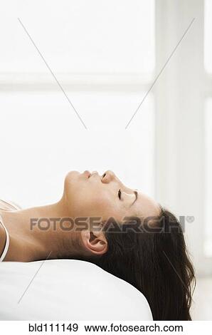 Stock Photo - Hispanic woman laying on bed. Fotosearch