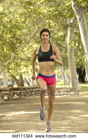 Picture - Hispanic woman running in park. Fotosearch