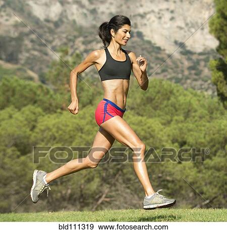 Stock Photo - Hispanic woman running in rural field. Fotosearch