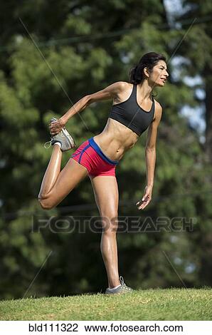 Stock Image - Hispanic woman stretching in rural field. Fotosearch