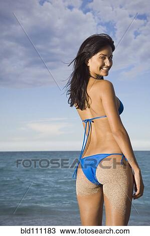 Stock Image - Hispanic woman wearing bikini on beach. Fotosearch