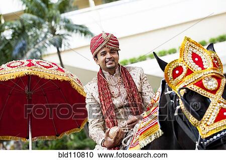 Stock Image - Indian groom riding horse in wedding procession. Fotosearch