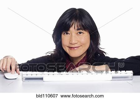Stock Photo - Japanese woman using computer keyboard and mouse. Fotosearch