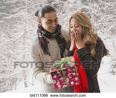 Man giving girlfriend gift in snow View Large Photo Image Stock Photograph - Man giving girlfriend gift in snow. Fotosearch