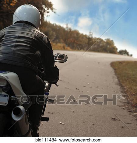 Man riding motorcycle on rural road View Large Photo Image Picture - Man riding motorcycle on rural road. Fotosearch