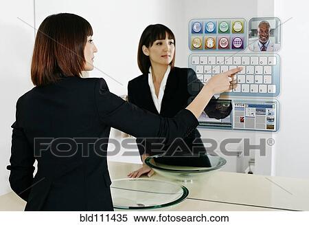 Stock Photography - Mixed race businesswoman using computer in mirror. Fotosearch