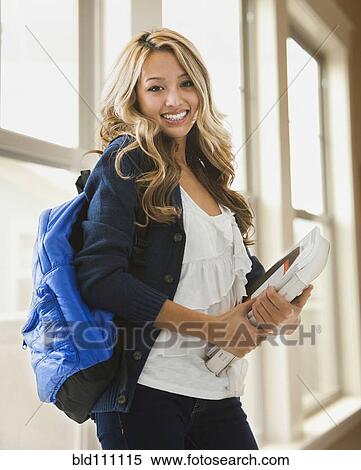 Stock Photography - Mixed race student carrying books on campus. Fotosearch