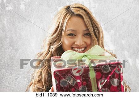 Stock Photo - Mixed race woman holding present in snow. Fotosearch
