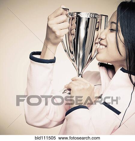 Stock Photography - Mixed race woman holding trophy. Fotosearch