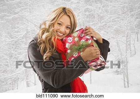 Mixed race woman hugging present in snow View Large Photo Image Stock Image - Mixed race woman hugging present in snow. Fotosearch