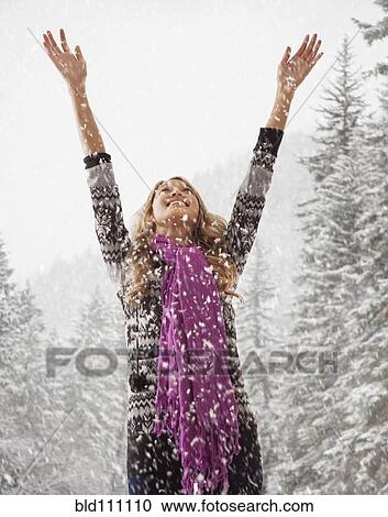Stock Image - Mixed race woman playing in snow. Fotosearch