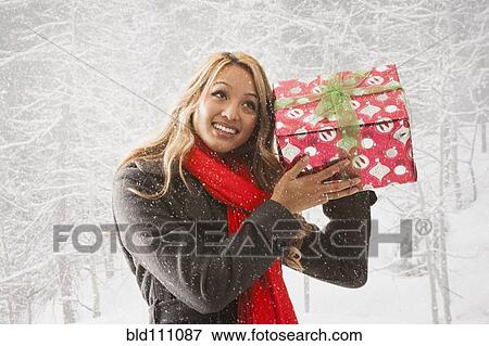 Stock Photo - Mixed race woman shaking present in snow. Fotosearch