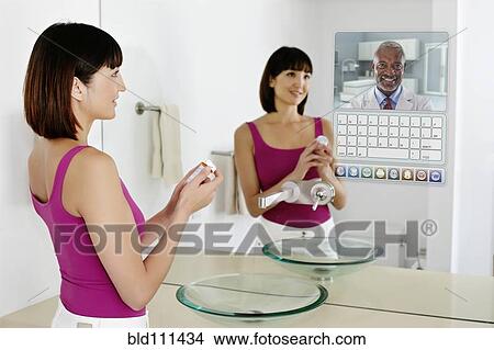 Picture - Mixed race woman using computer in mirror. Fotosearch