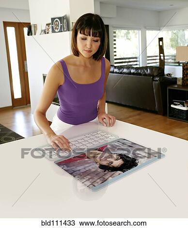 Stock Image - Mixed race woman using computer in table. Fotosearch
