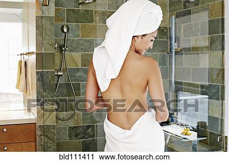 Stock Image - Mixed race woman wrapped in towels in bathroom. Fotosearch
