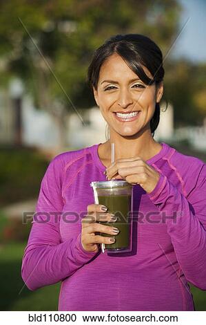 Stock Image - Pregnant Hispanic woman having health drink. Fotosearch
