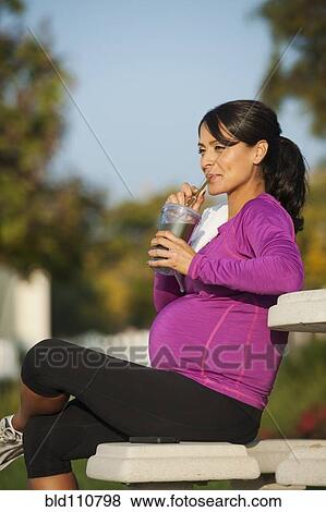 Stock Photo - Pregnant Hispanic woman having health drink. Fotosearch