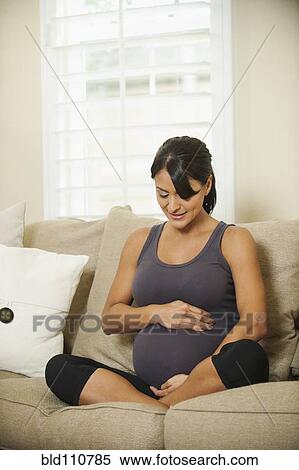 Stock Photography - Pregnant Hispanic woman holding her belly. Fotosearch