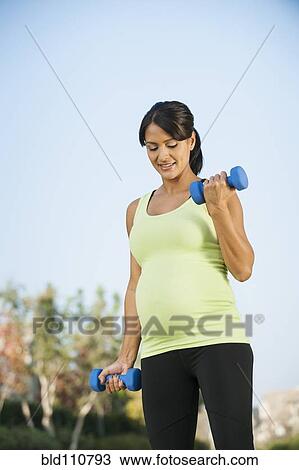 Pregnant Hispanic woman lifting weights outdoors View Large Photo Image Stock Image - Pregnant Hispanic woman lifting weights outdoors. Fotosearch