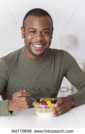 Smiling Black man eating breakfast View Large Photo Image Stock Photo - Smiling Black man eating breakfast. Fotosearch