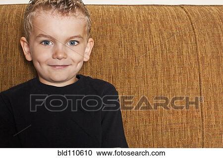 Smiling Caucasian boy sitting on sofa View Large Photo Image Stock Image - Smiling Caucasian boy sitting on sofa. Fotosearch