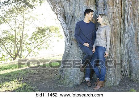 Stock Image - Smiling couple hugging in park. Fotosearch