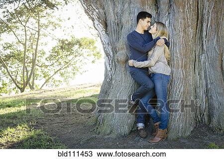 Stock Image - Smiling couple hugging in park. Fotosearch