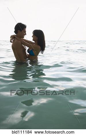 Picture - Smiling couple hugging in water. Fotosearch
