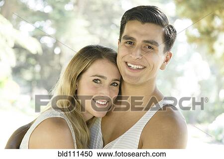 Stock Image - Smiling couple hugging outdoors. Fotosearch