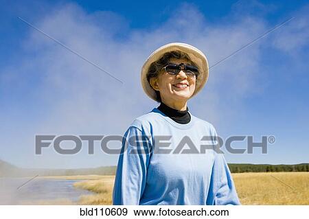 Stock Photo - Smiling Japanese woman standing near lake. Fotosearch