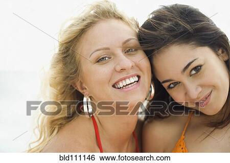 Stock Photograph - Smiling women standing on beach. Fotosearch