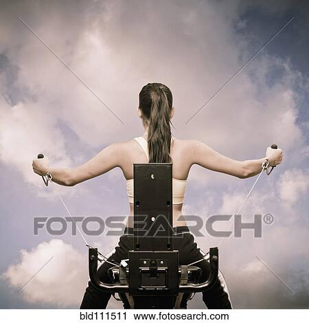 Stock Image - Woman using exercise machine outdoors. Fotosearch