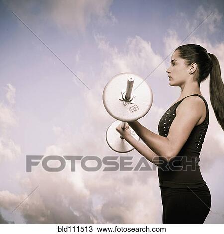Stock Image - Woman using lifting weights outdoors. Fotosearch