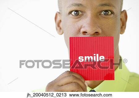 Portrait of a businessman holding up a card with the word smile written View Large Photo Image Stock Image - Portrait of a businessman holding up a card with the word smile written. Fotosearch