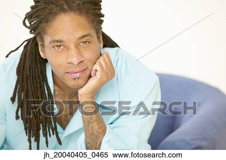 Portrait of a young man sitting on a couch View Large Photo Image Stock Photography - Portrait of a young man sitting on a couch. Fotosearch