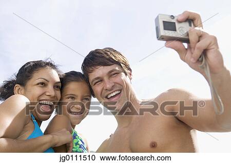 Stock Image - Young man taking a snap of his wife, child and himself. Fotosearch